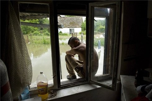 Egy fiú ül lakóházának ablakában a Tolna megyei Bátán 2013. június 11-én. A településnél reggel 761 centiméteres vízállást mértek a Dunán. A tetőzés június 12-én délután 775 centiméteren várható, az előre jelzett szint 34 centiméterrel haladhatja meg a 2002-es árvíz idején mért, eddigi legmagasabb, 741 centiméteres vízállást. MTI Fotó: Koszticsák Szilárd