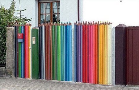 A hófehér ház fal kiemeli a színes ceruza kerítés vidám hangulatát. Feltételezhetően gyerekek is lakják a házat.