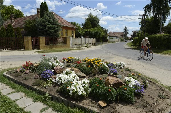Virágok és egy biciklista a Dózsa György úton, a Pest megyei Sülysápon 2013. július 12-én. Sülysáp azon tizennyolc település egyike, amelynek városi címet adományozott a köztársasági elnök 2013. július 15-ei hatállyal. MTI Fotó: Kovács Tamás